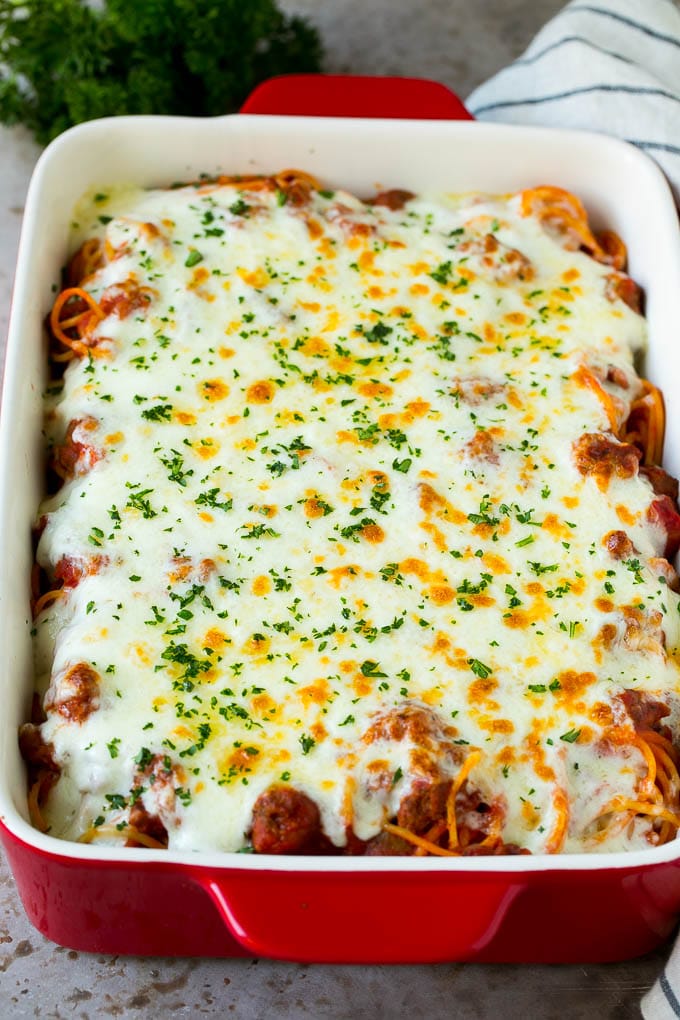 Spaghetti in a baking dish with melted cheese baked on top.