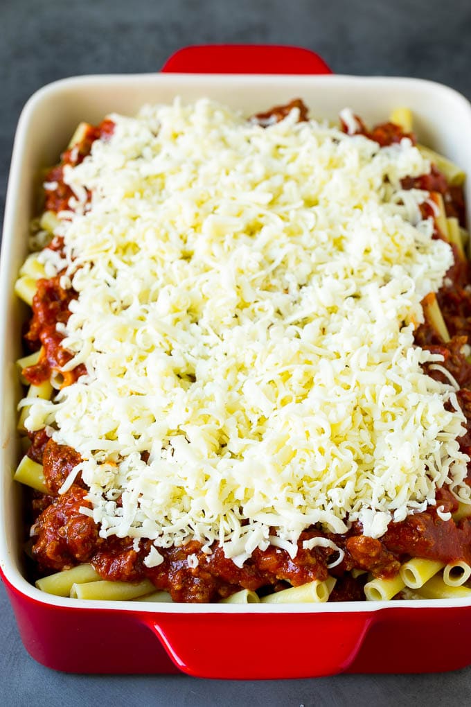 A baking dish of pasta topped with shredded cheese.