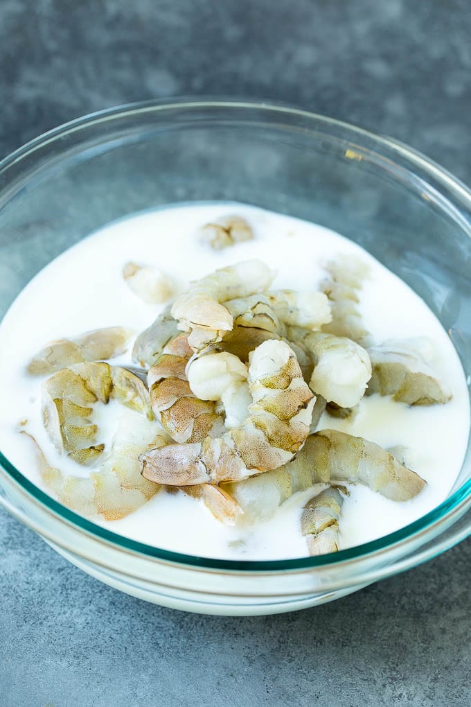 Raw shrimp in a bowl of buttermilk.