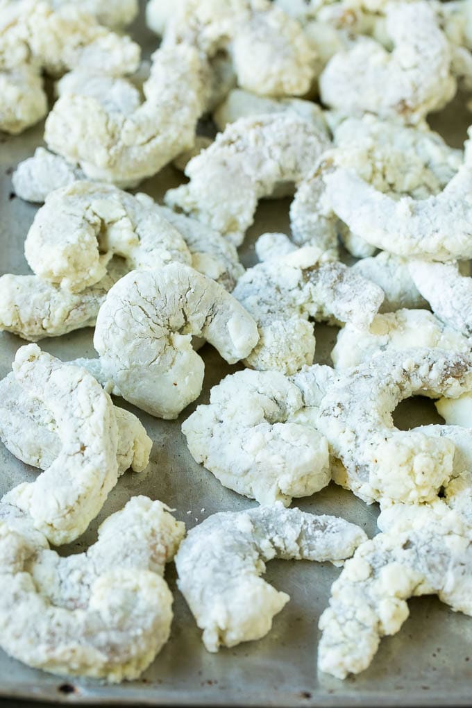 Shrimp coated in cornstarch on a sheet pan.