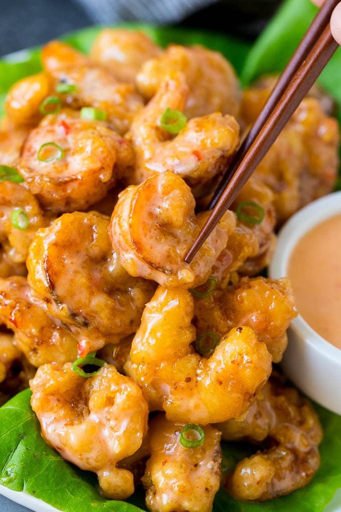 A pair of chopsticks picking up bang bang shrimp.