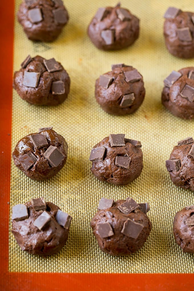 Balls of cookie dough with chocolate pieces pressed into the tops.