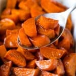 A spoon serving up a portion of candied sweet potatoes.