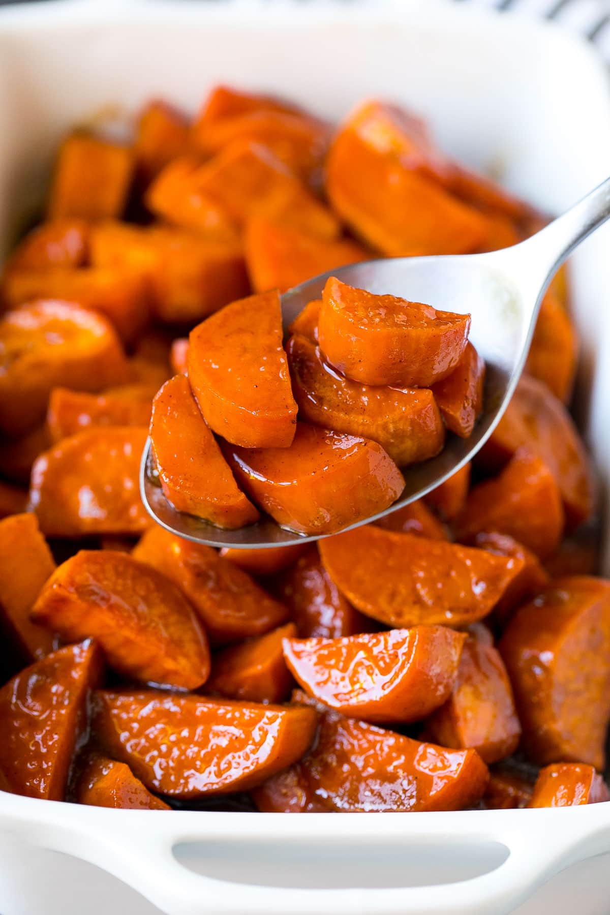 A spoon serving up a portion of candied sweet potatoes.