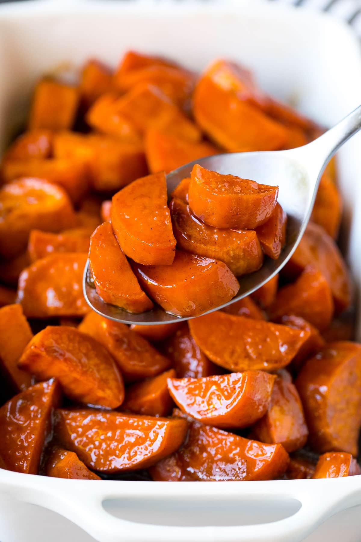 A spoon serving up a portion of candied sweet potatoes.