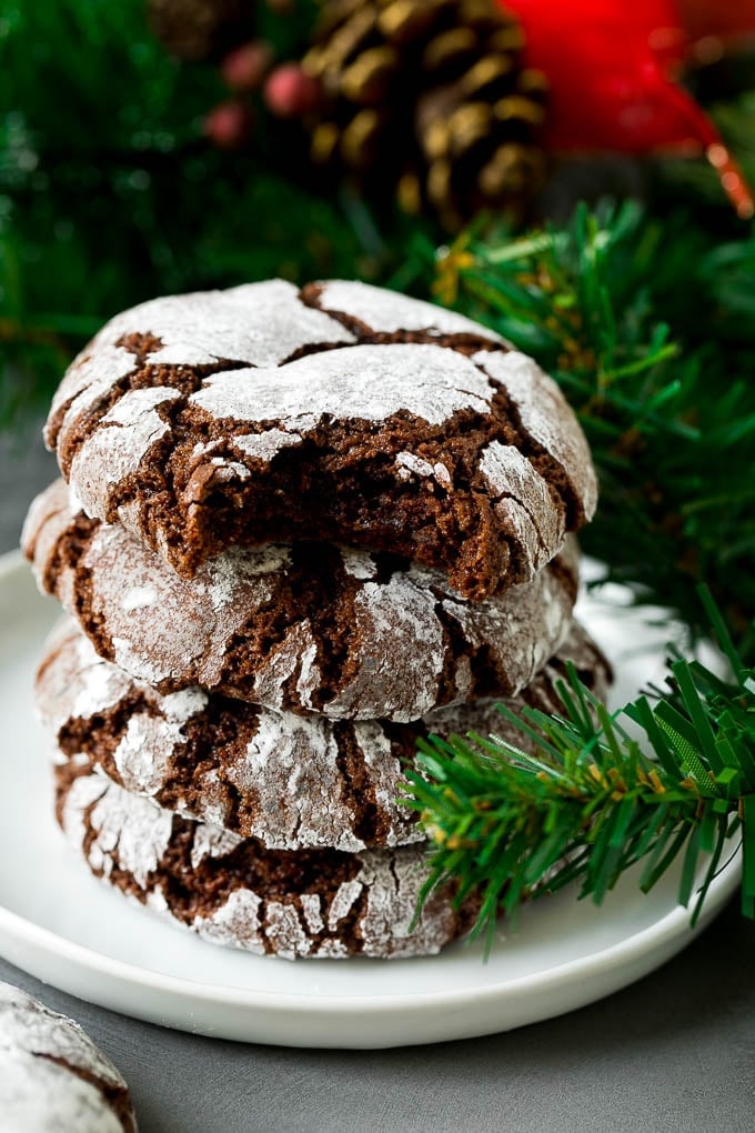 A stack of chocolate crinkle cookies with a bite taken out of one.