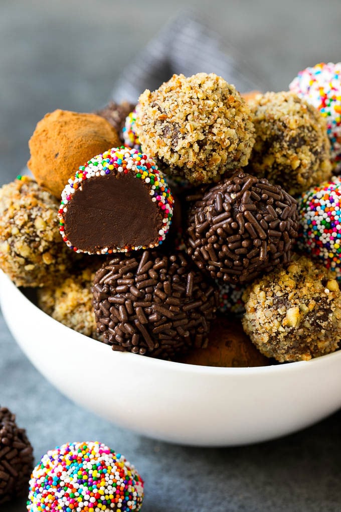 A bowl of chocolate truffles coated in an assortment of toppings.