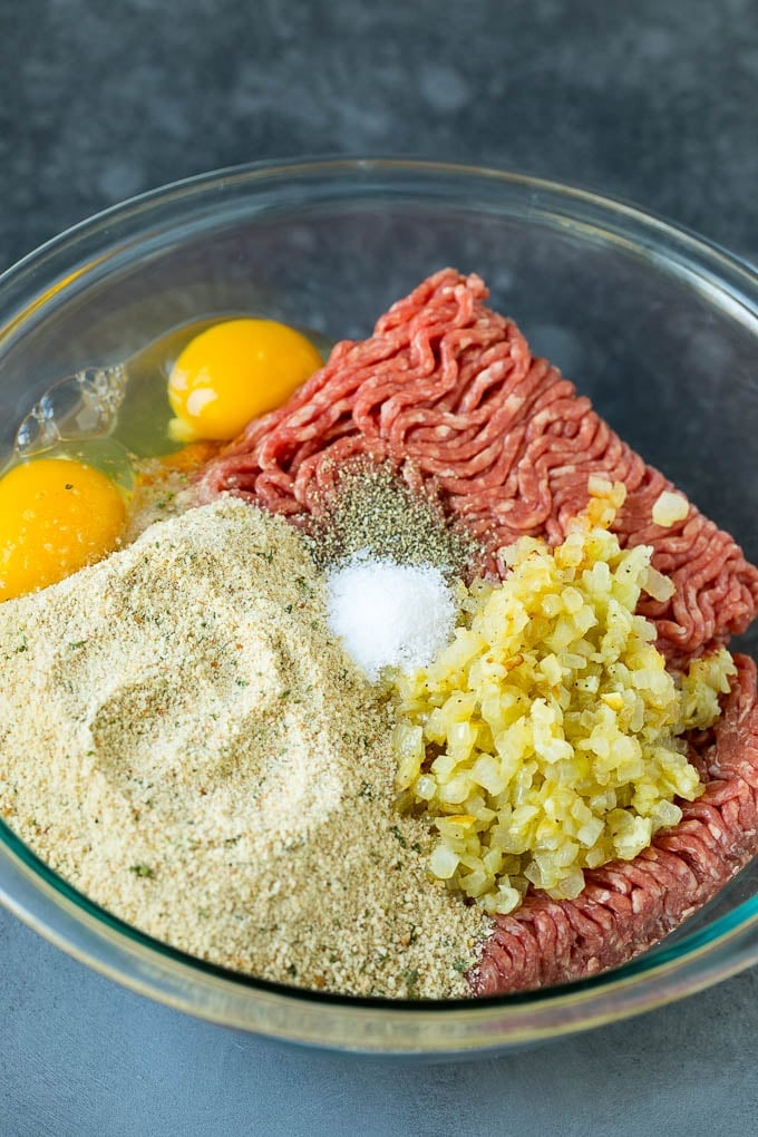 Ground beef, breadcrumbs, eggs, onion and seasonings in a bowl.