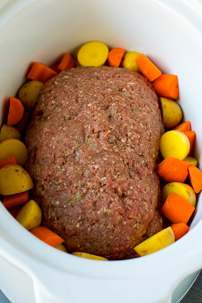 Ground beef shaped into a loaf in a crockpot.