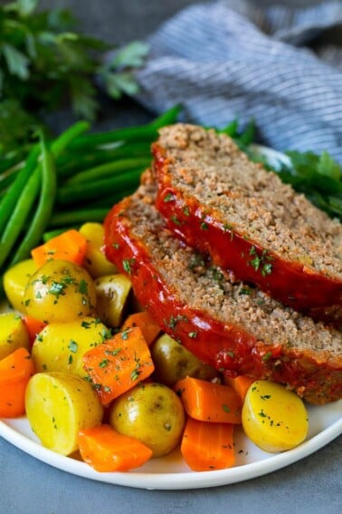 Slices of crockpot meatloaf served with carrots, potatoes and green beans.