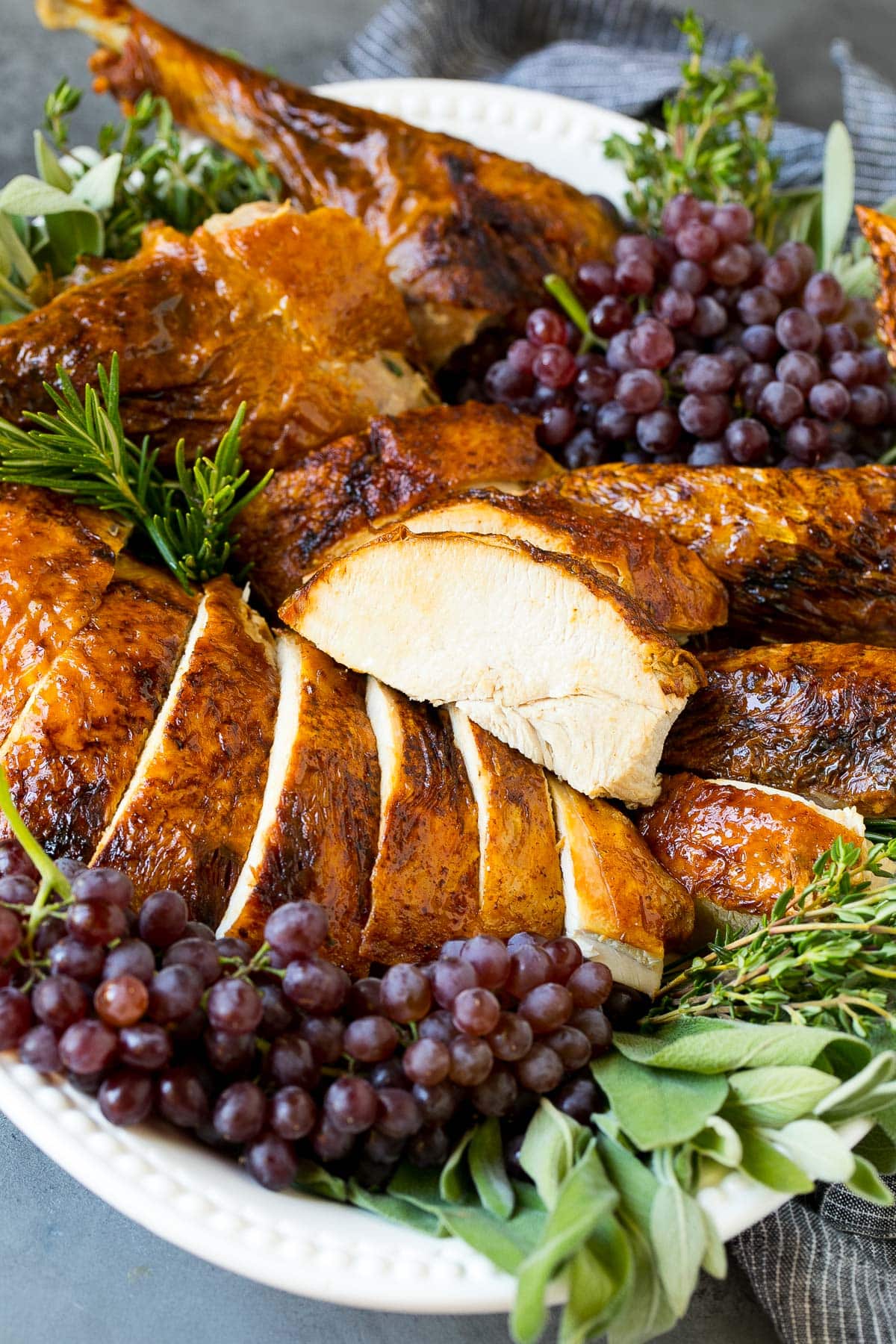 Sliced deep fried turkey garnished with grapes and herbs.