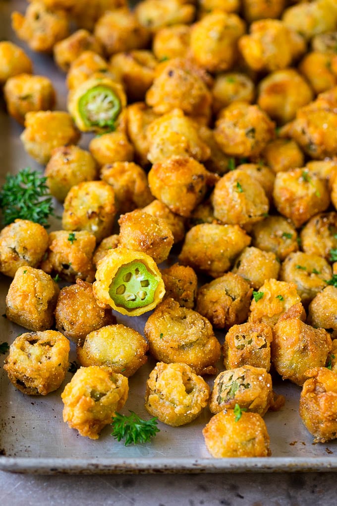 Fried okra on a sheet pan, garnished with chopped parsley.