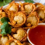 A plate of fried wonton served with sweet chili sauce.