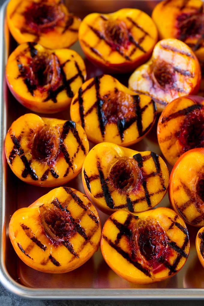 Grilled peach halves arranged on a tray.