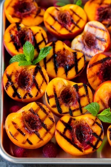 Grilled peaches garnished with raspberries and fresh mint.