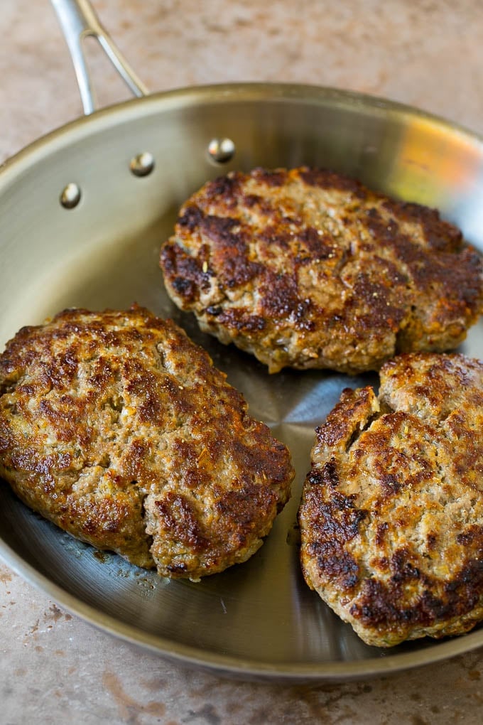 Seared hamburger patties in a pan.