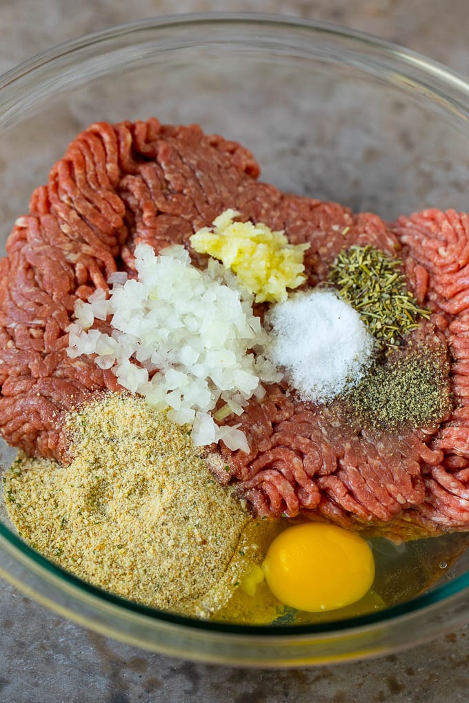 Ground beef with onions, breadcrumbs and seasonings in a mixing bowl.