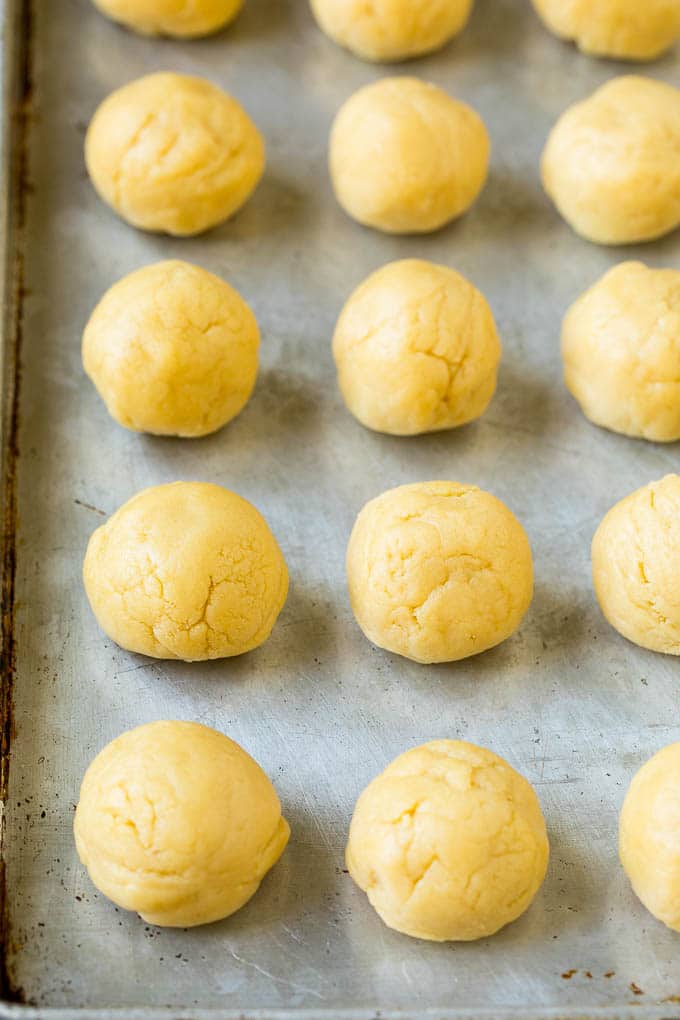 Balls of cookie dough on a sheet pan.