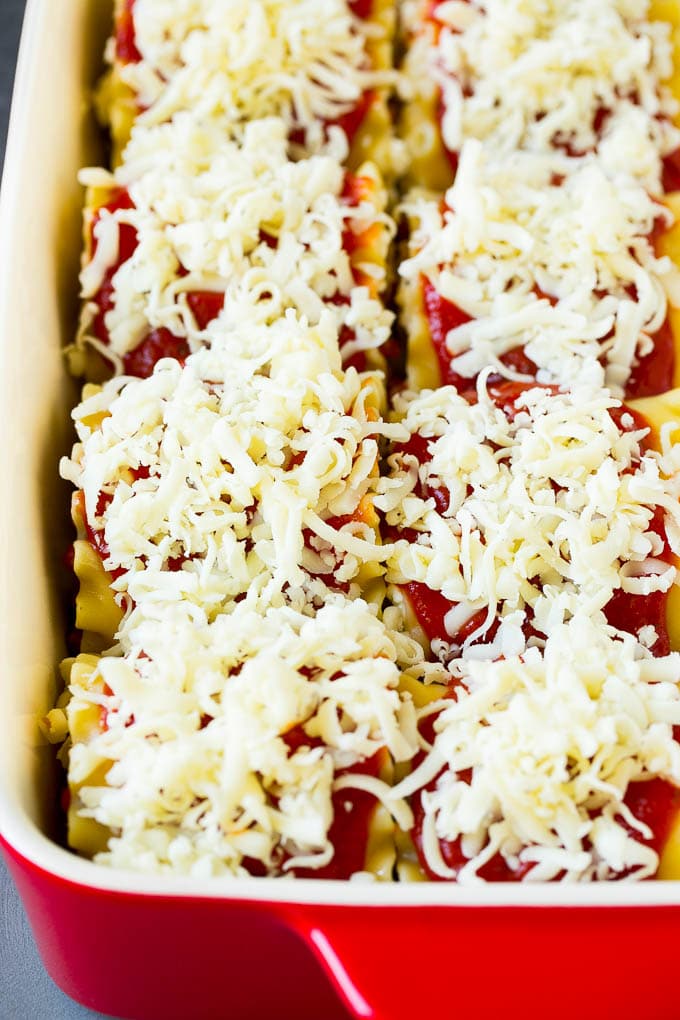 Lasagna noodles rolled up in a baking dish and topped with sauce and melted cheese.