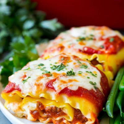 Lasagna roll ups with meat sauce, served with a side of green beans.