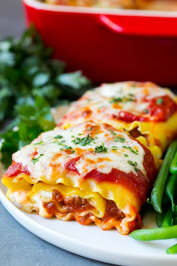 Lasagna roll ups with meat sauce, served with a side of green beans.