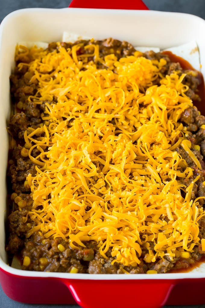 Layers of tortillas, ground beef and shredded cheese in a baking dish.