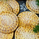 Pizzelle cookies cooked to golden brown and coated in powdered sugar.