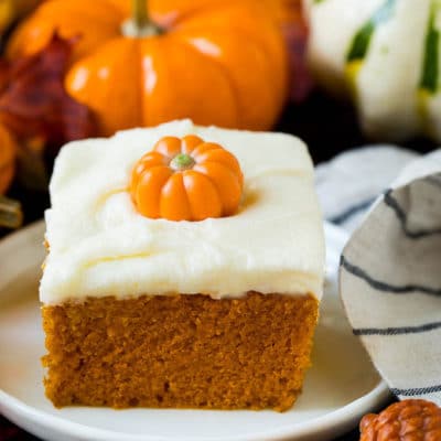 A slice of pumpkin cake topped with cream cheese frosting.