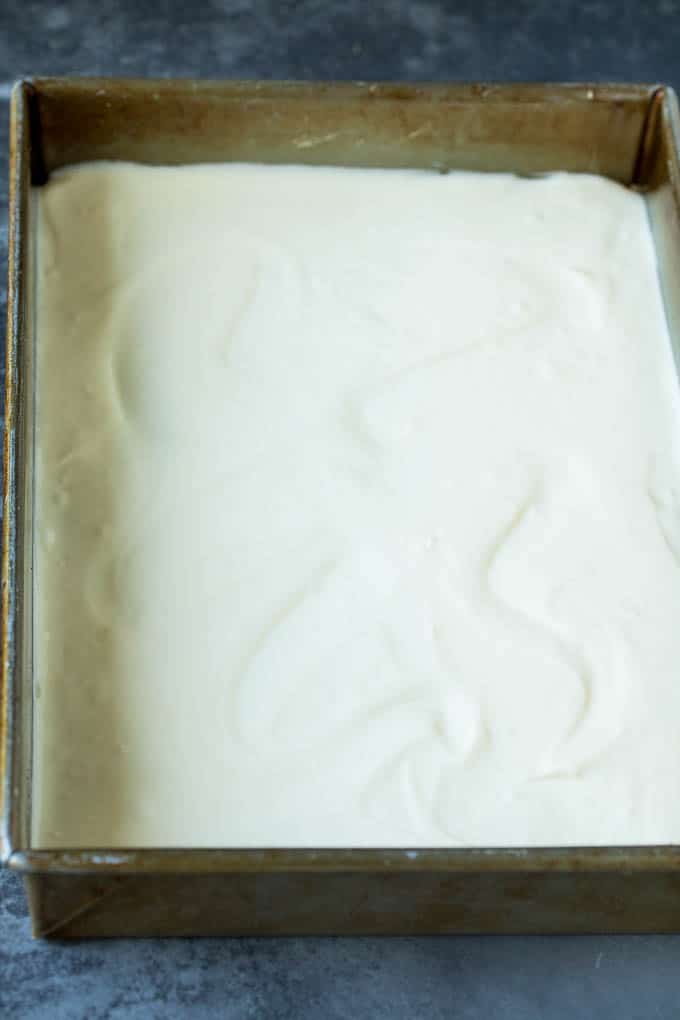 A layer of vanilla cheesecake batter in a baking pan.