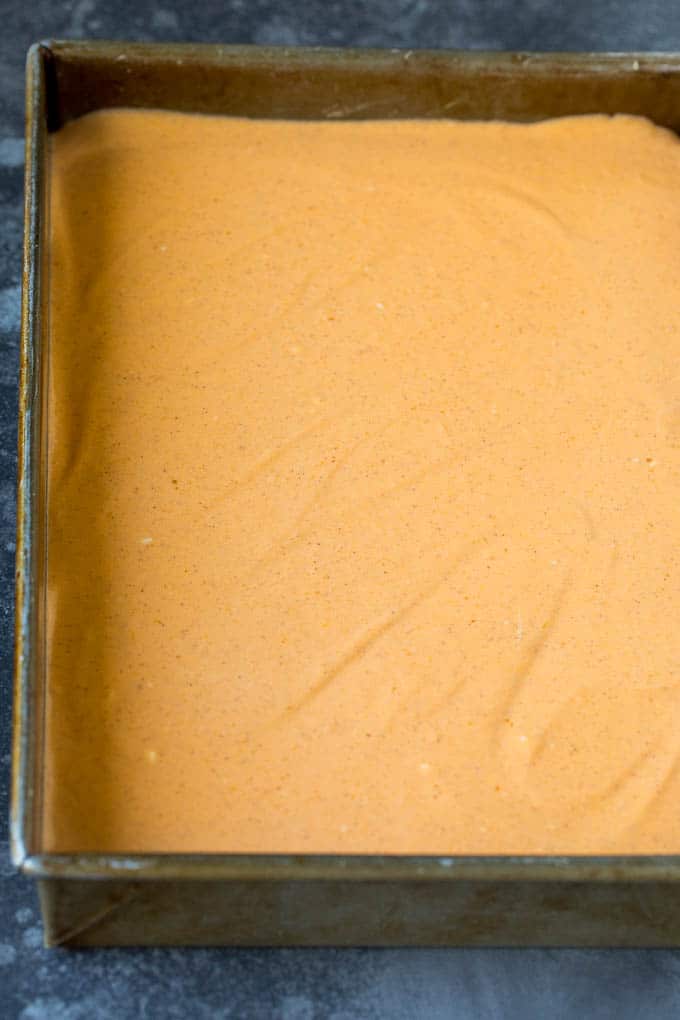 A layer of pumpkin cheesecake batter in a rectangular pan.