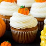 Pumpkin cupcakes topped with cream cheese frosting and candy pumpkins.