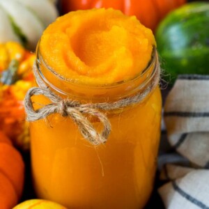 A jar of pumpkin puree surrounded by fall produce.