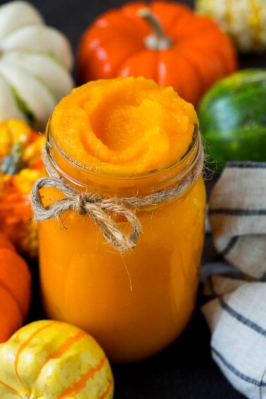 A jar of pumpkin puree surrounded by fall produce.
