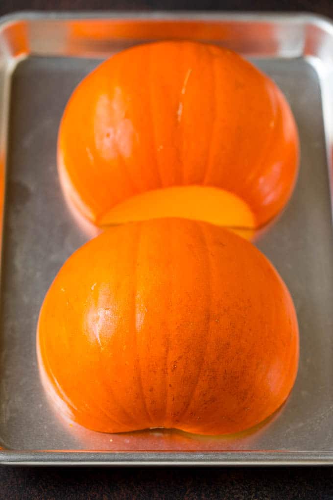 Pumpkin Puree Recipe #pumpkin #baking #fall #thanksgiving #dinneratthezoo A pumpkin cut in half on a sheet pan.