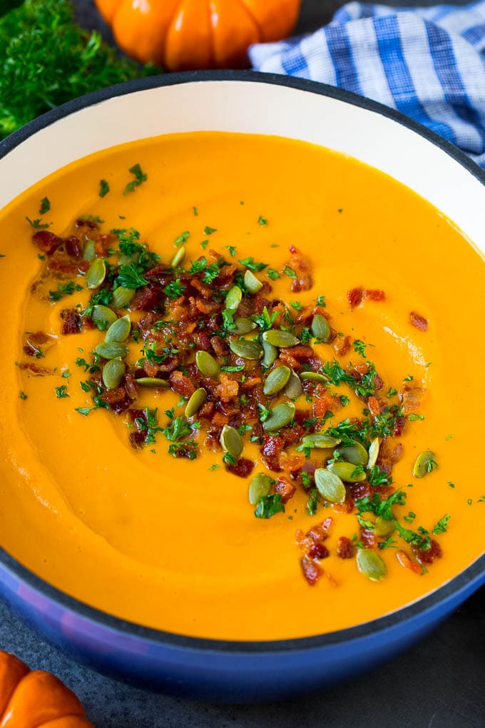 A pot of creamy pumpkin soup with bacon and herbs.