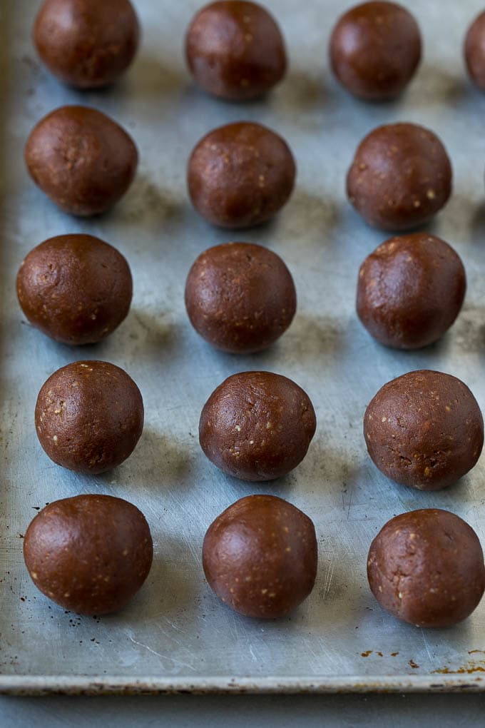 Balls of chocolate and cookie crumbs on a baking sheet.