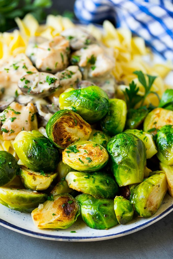 Sauteed brussels sprouts served alongside chicken and noodles.
