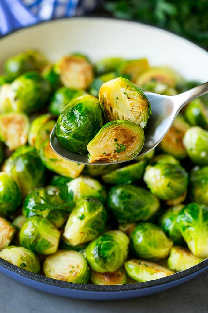 A spoon holding up a serving of cooked brussels sprouts.