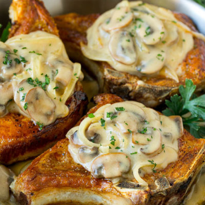 A pan of smothered pork chops topped with mushroom and onion gravy.