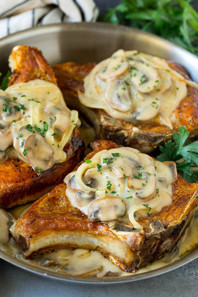 A pan of smothered pork chops topped with mushroom and onion gravy.