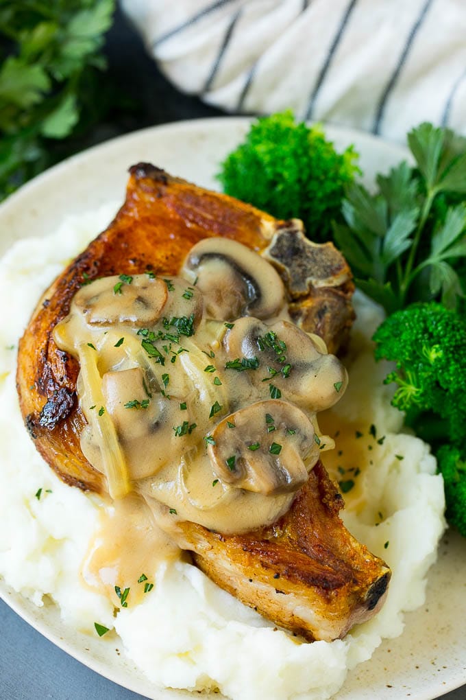 Smothered pork chops served with mashed potatoes and broccoli.