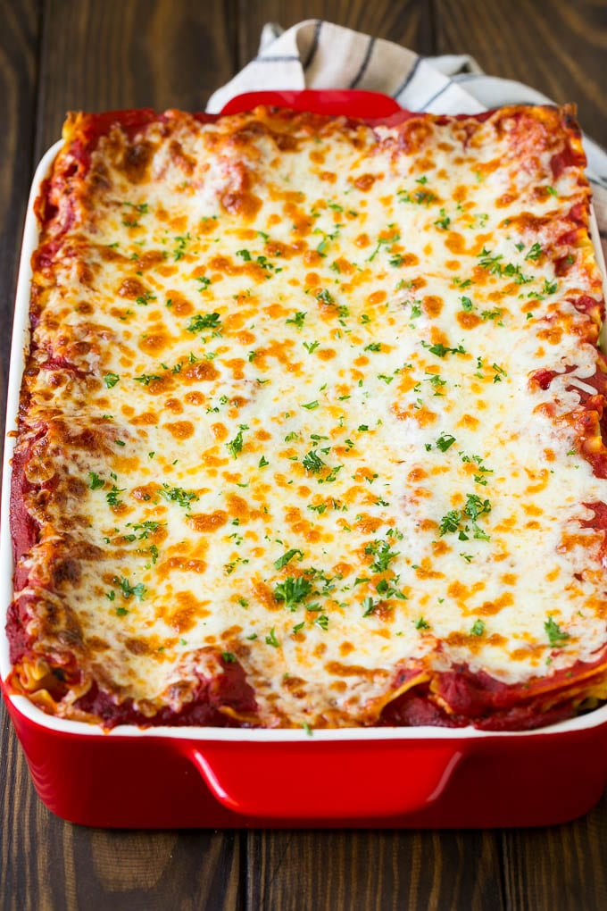 A baked lasagna topped with melted cheese and chopped parsley.