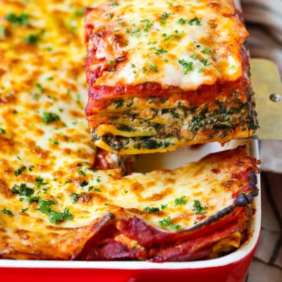 A spatula serving up a slice of spinach lasagna.