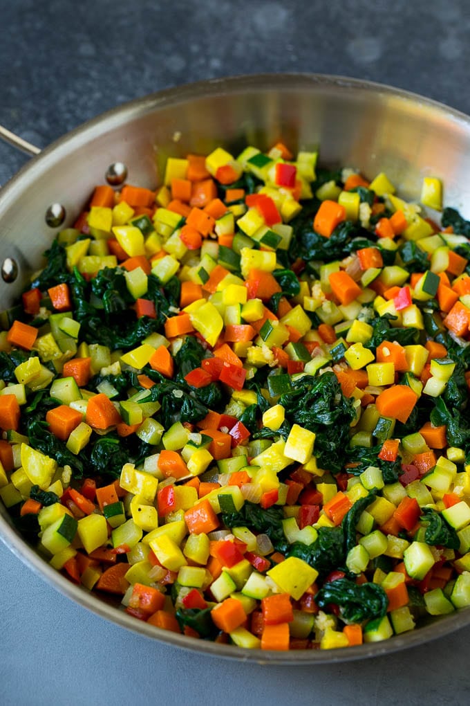 Zucchini, squash, spinach, carrots and peppers in a skillet.