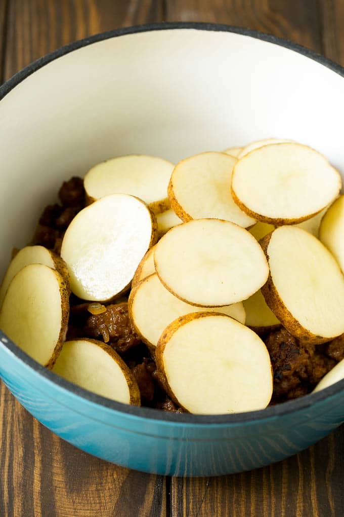 Sausage and sliced potatoes in a pot.