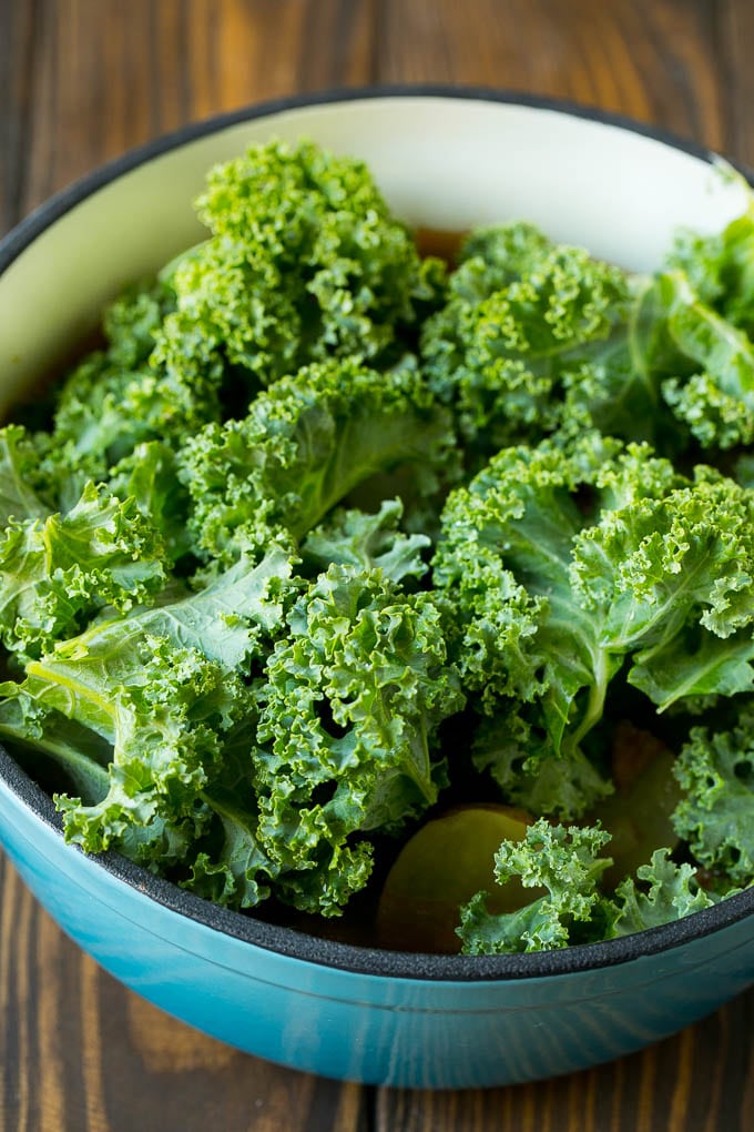 Fresh kale leaves going into a pot of soup.