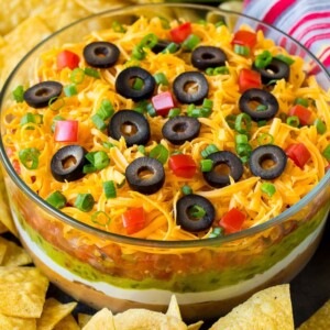 A bowl of 7 layer dip surrounded with tortilla chips.