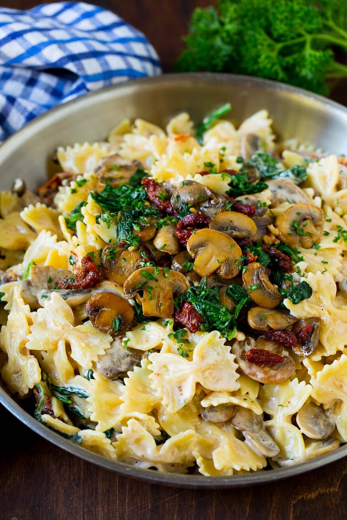 Farfalle pasta with spinach and mushrooms in a creamy sauce.