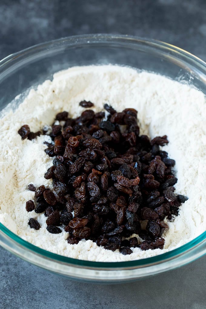 Flour, sugar, butter, baking powder and raisins in a mixing bowl.