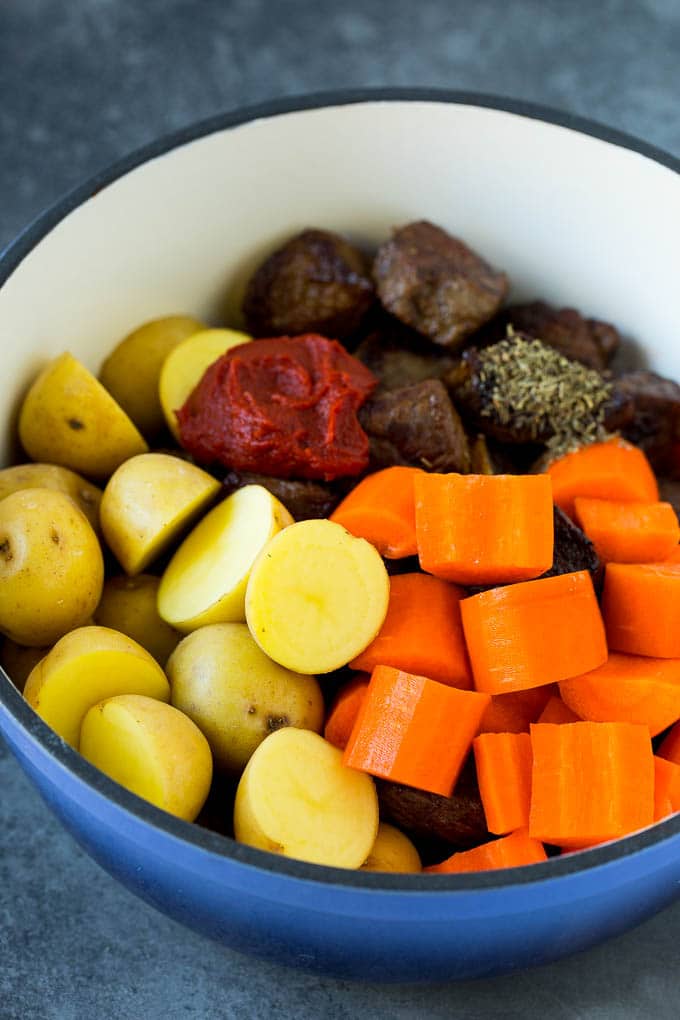 Beef, potatoes, carrots and tomato paste in a pot.